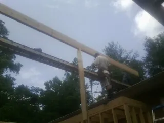 Carpenter setting a ridge beam over a new addition frame in Cambridge
